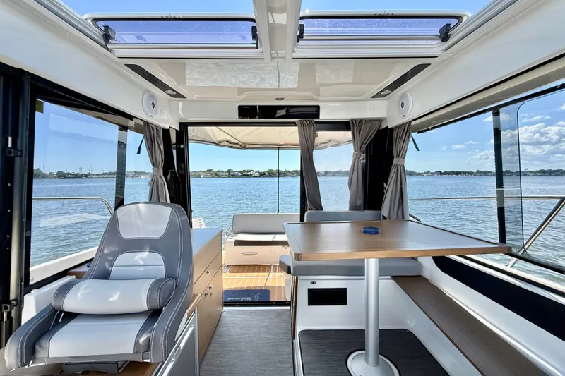 Slide: The Image of Interior of 2019 Jeanneau NC 895 boat with seating and table, overlooking serene water view. - 20
