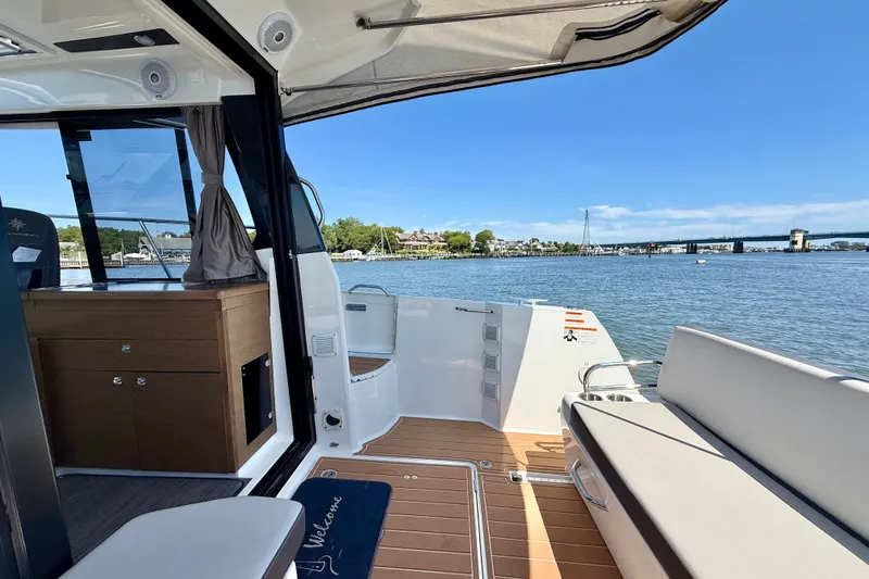 Slide: The Image of 2019 Jeanneau NC 895 boat interior with open deck, overlooking serene waterfront and bridge. - 9