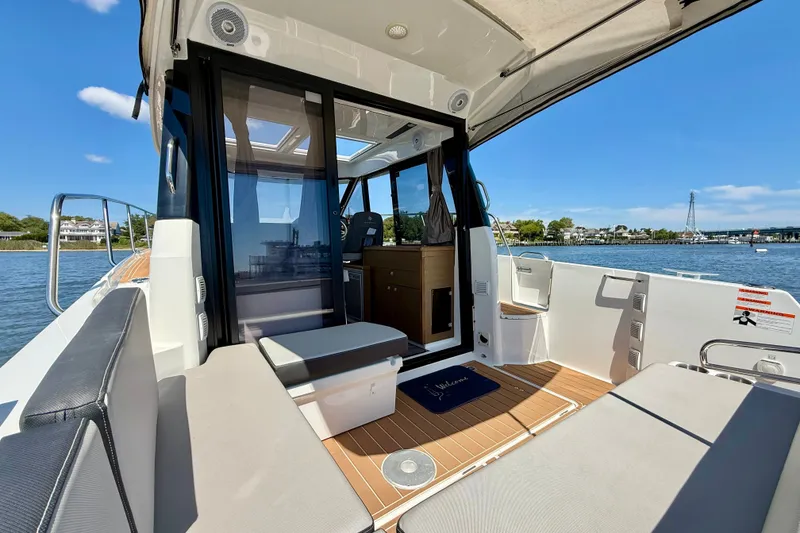 Slide: The Image of 2019 Jeanneau NC 895 boat interior with seating, open water view, and sunny weather. - 8
