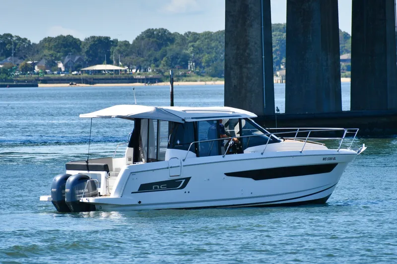 Slide: The Image of 2019 Jeanneau NC 895 boat cruising on a calm river near a bridge. - 4