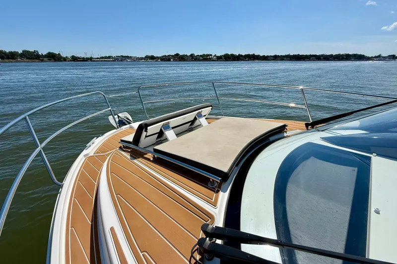 Slide: The Image of 2019 Jeanneau NC 895 boat deck with sunpad, overlooking calm waters and distant shoreline. - 24