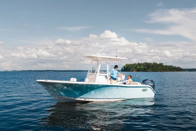 Slide: The Image of A 2027 Sea Hunt Ultra 229 boat on calm water with two people on board. - 2