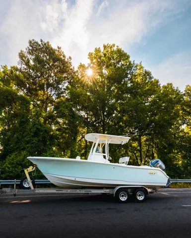 Slide: The Image of A 2027 Sea Hunt Ultra 229 boat on a trailer, set against a wooded backdrop. - 14