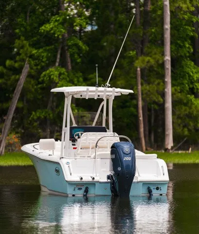 Slide: The Image of A 2027 Sea Hunt Ultra 229 boat on calm water, surrounded by trees. - 3