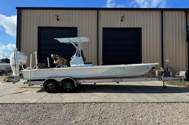 The Image of 2021 Haynie 25 Magnum boat on trailer, parked outside a large garage. - 1