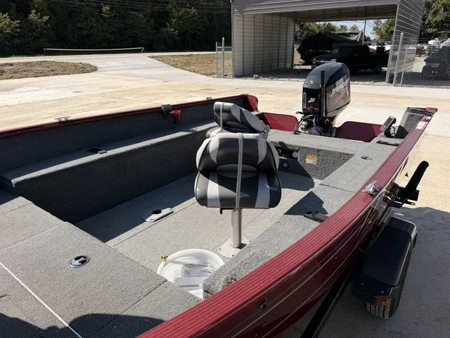 Slide: The Image of A 2009 Lund 1625 REBEL XL boat with gray seats and an outboard motor, parked on a trailer. - 13