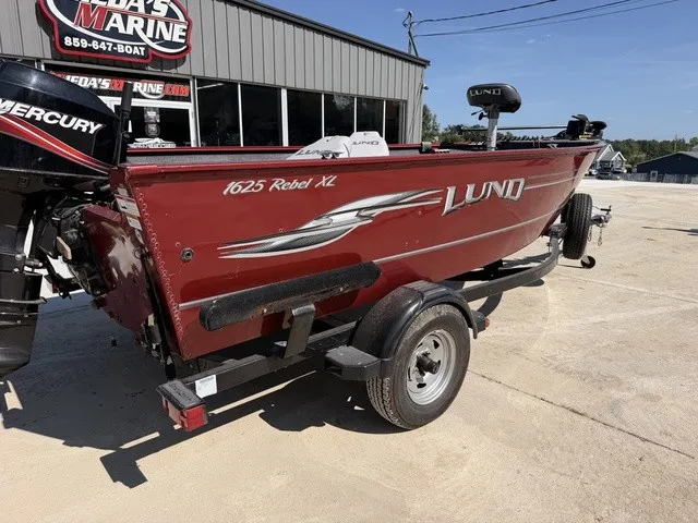 Slide: The Image of A red 2009 Lund 1625 Rebel XL boat on a trailer, featuring a Mercury outboard motor. - 3