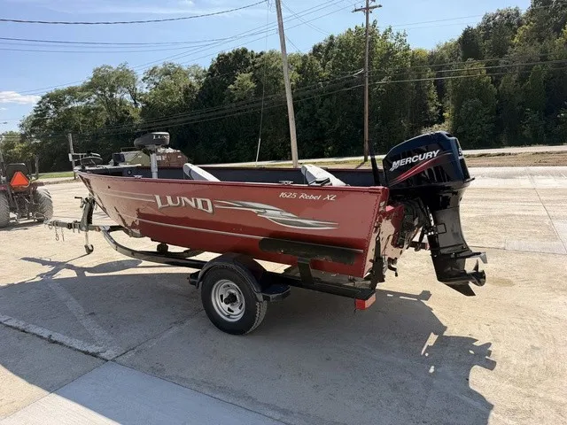 Slide: The Image of A red 2009 Lund 1625 Rebel XL boat is on a trailer, with a Mercury outboard motor. - 14