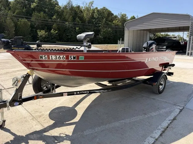 Slide: The Image of A red 2009 Lund 1625 REBEL XL boat on a trailer, parked on a concrete lot. - 9
