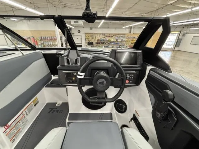 Slide: The Image of The image shows the cockpit of a 2027 Axis Wake Research T250 boat. It features a modern steering wheel, large display, and gray upholstery. - 9