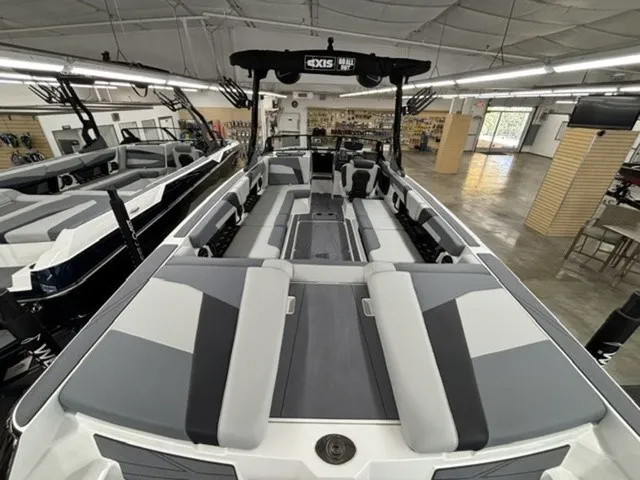 Slide: The Image of The image shows the spacious deck of a 2027 Axis Wake Research T250 boat in a showroom. - 6