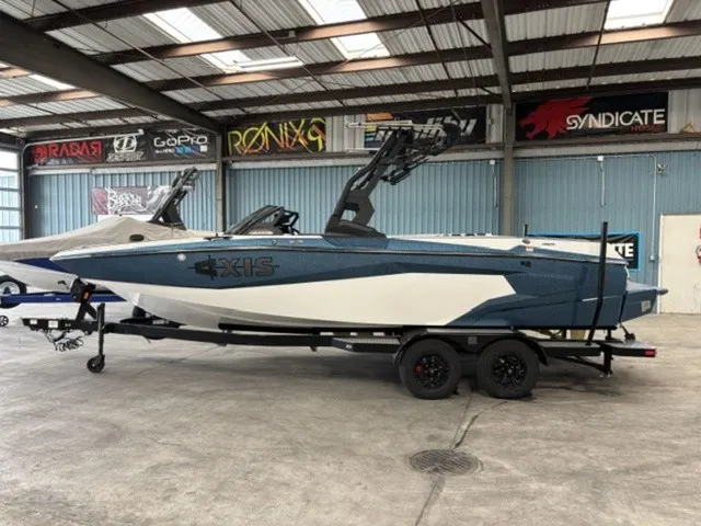 The Image of An Axis Wake Research A225 boat from 2027 sits on a trailer in a warehouse. - 1