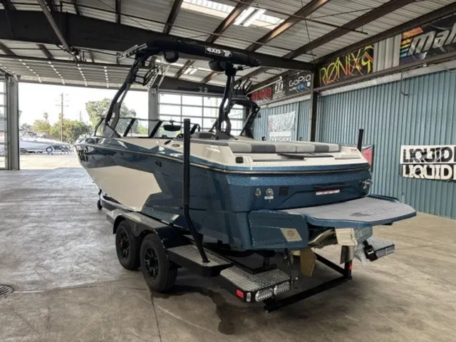 Slide: The Image of Axis Wake Research A225 2027 in a warehouse, featuring a blue hull and black wakeboard tower. - 3