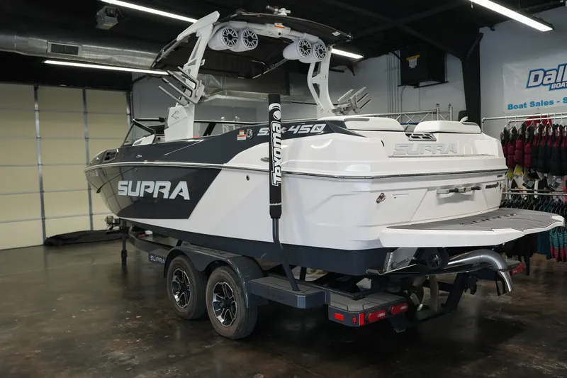 Slide: The Image of 2023 Supra SA 450 boat on trailer in showroom, rear view. - 2