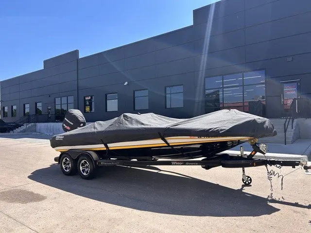 Slide: The Image of A 2015 Triton 20 TrX boat with a cover on a trailer in front of a building. - 22