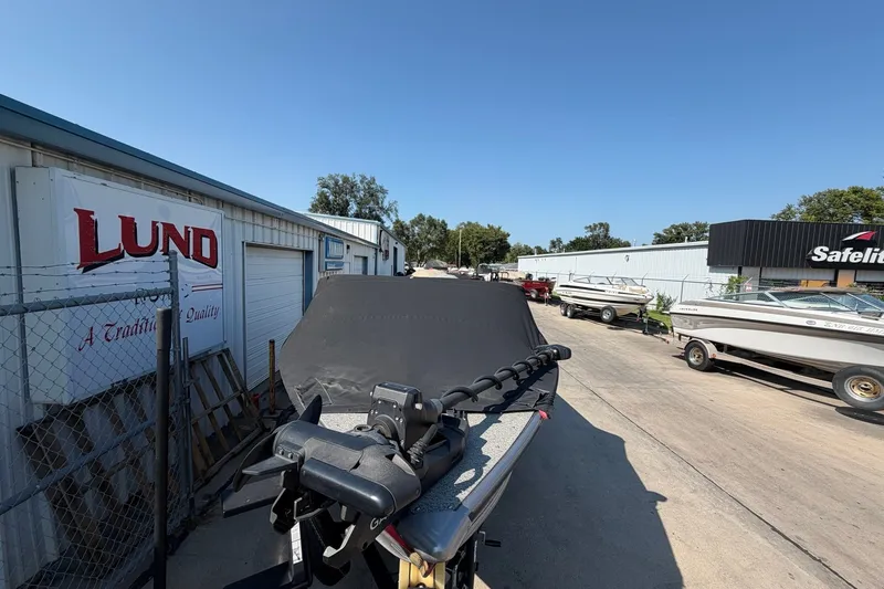 Slide: The Image of 2024 Lund 1875 Fisherman boat covered, parked outside dealership on sunny day. - 10