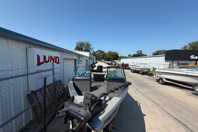 Slide: The Image of 2024 Lund 1875 Fisherman boat displayed outdoors at a dealership. - 9