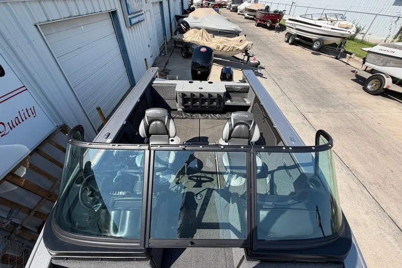 Slide: The Image of 2024 Lund 1875 Fisherman boat with dual seats and windshield, parked outdoors. - 11