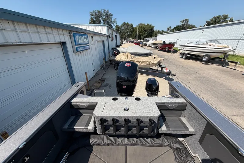 Slide: The Image of 2024 Lund 1875 Fisherman boat at dealership, featuring Yamaha outboard motor and storage compartments. - 16