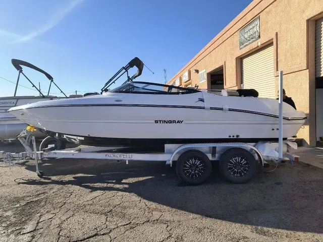 Slide: The Image of A white 2027 Stingray 23 OSX boat on a trailer in front of a building. - 34