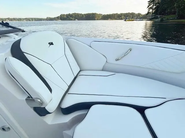 Slide: The Image of The image shows the luxurious white upholstery of a Stingray 23 OSX, situated on a calm lake. - 18