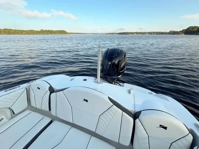Slide: The Image of The image shows the stern of a Stingray 23 OSX boat on a calm lake. - 22