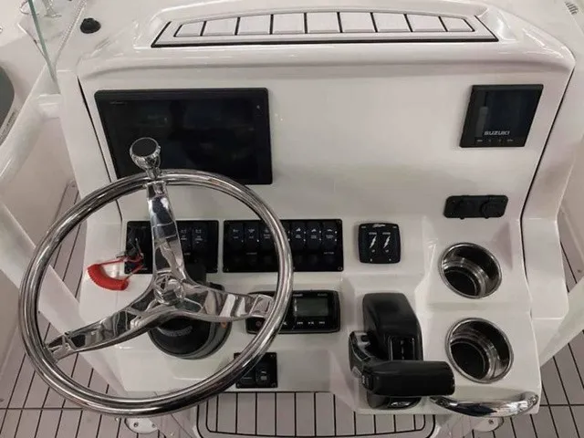Slide: The Image of The image shows the helm of a Stingray 20 CC boat. It features a sleek design with a shiny steering wheel, multiple instruments, and cup holders. - 9