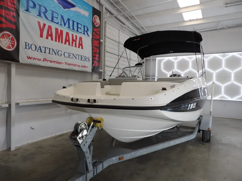 Slide: The Image of A 2013 Bayliner 190 Deck Boat on a trailer in a showroom setting. - 3
