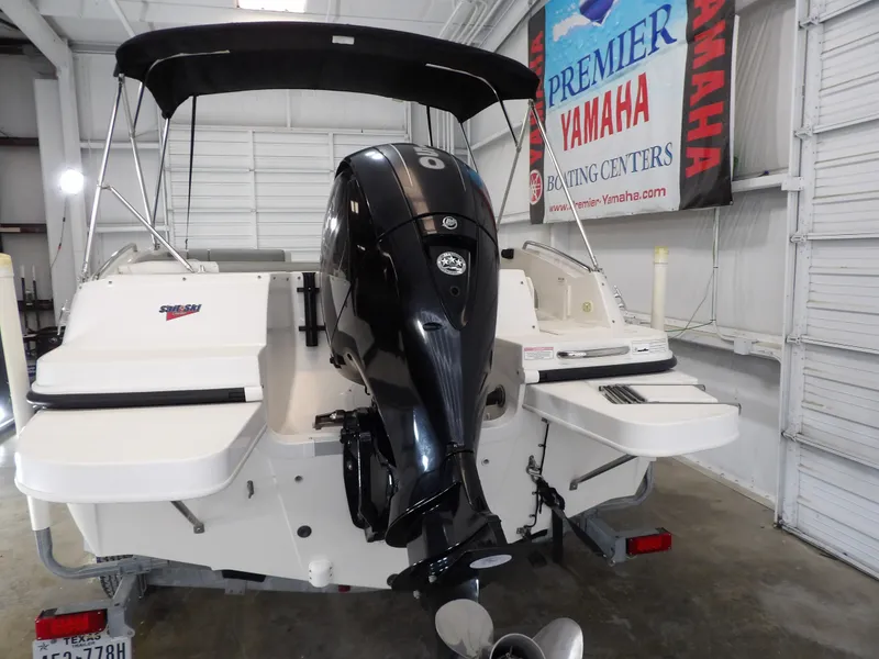 Slide: The Image of A 2013 Bayliner 190 Deck Boat with an outboard motor in a storage facility. - 7