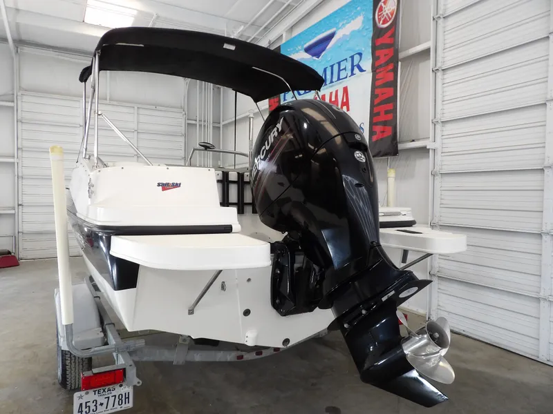 Slide: The Image of A 2013 Bayliner 190 Deck Boat in a warehouse. It features a large outboard motor. - 6