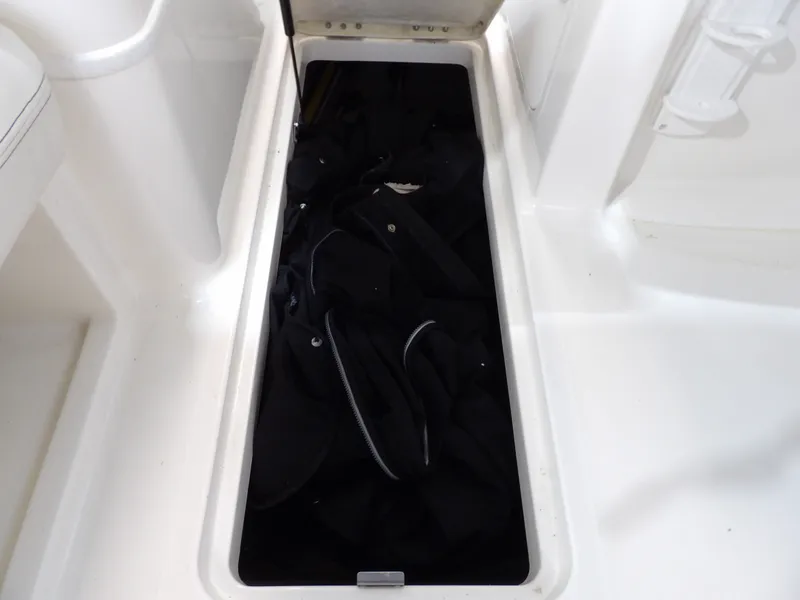 Slide: The Image of An open storage compartment on a 2013 Bayliner 190 Deck Boat, filled with black items. - 26