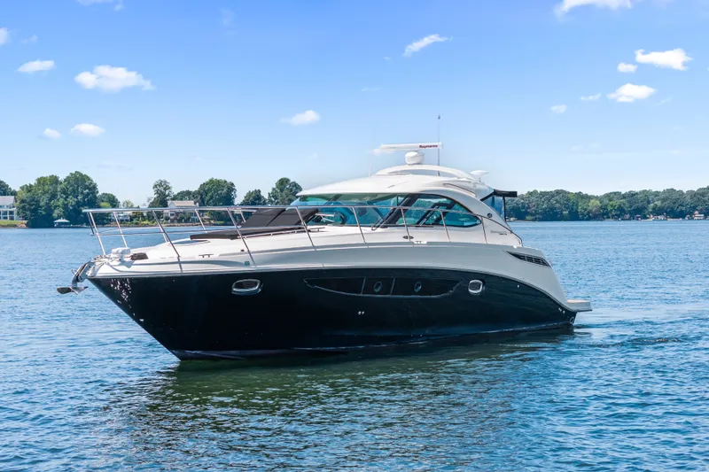 Slide: The Image of 2013 Sea Ray 410 Sundancer yacht cruising on a serene lake under a clear blue sky. - 4