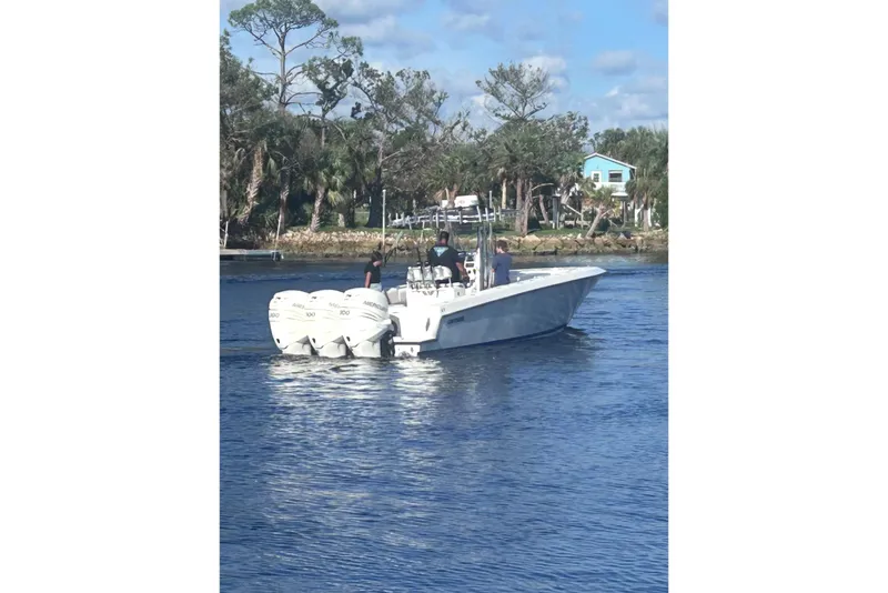 Slide: The Image of 2005 Contender 35 ST boat with triple outboard engines on a calm waterway. - 2