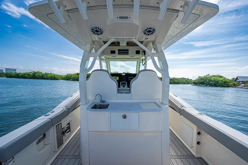 Slide: The Image of 2021 Scout 330 LXF boat interior with helm and seating, on a sunny day. - 28