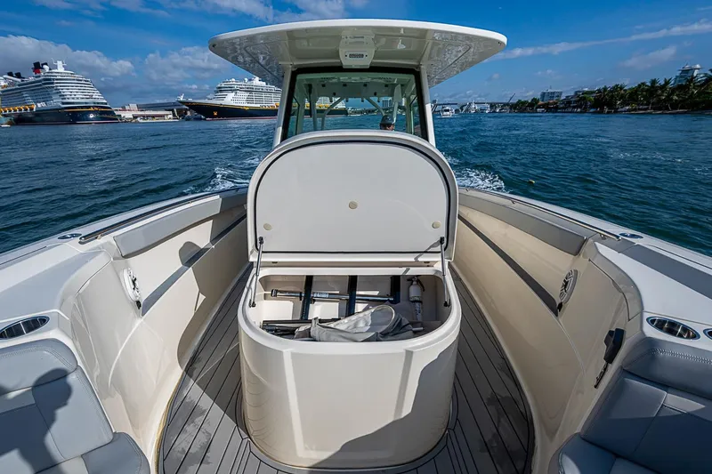 Slide: The Image of 2021 Scout 330 LXF boat cruising near large ships in a sunny harbor. - 15