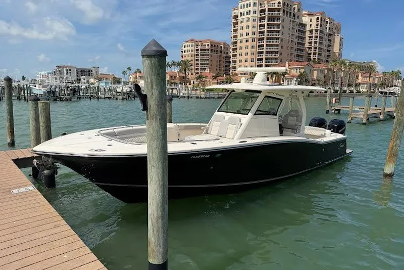 The Image of 2021 Scout 330 LXF boat docked in marina with waterfront buildings. - 0