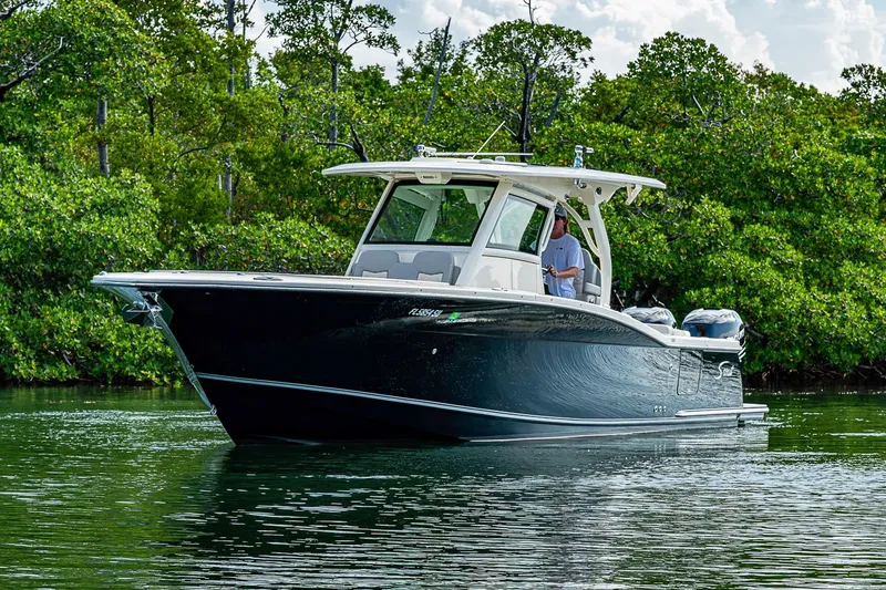 Slide: The Image of 2021 Scout 330 LXF boat cruising on calm water near lush greenery. - 3