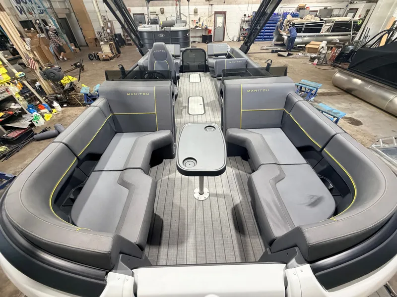 Slide: The Image of Interior view of a 2023 Manitou 22 Explore Tritoon with gray seating and a central table. - 2