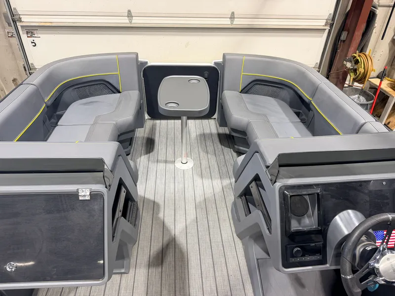 Slide: The Image of The image shows the interior of a 2023 Manitou 22 Explore Tritoon with gray seating and a table. - 32