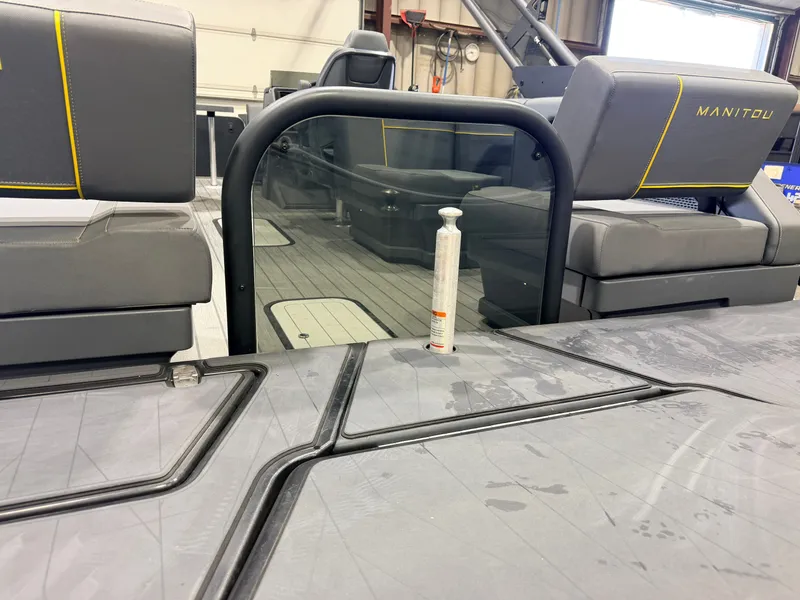 Slide: The Image of The image shows the interior of a Manitou 22 Explore Tritoon with gray seating and a glass railing. - 50