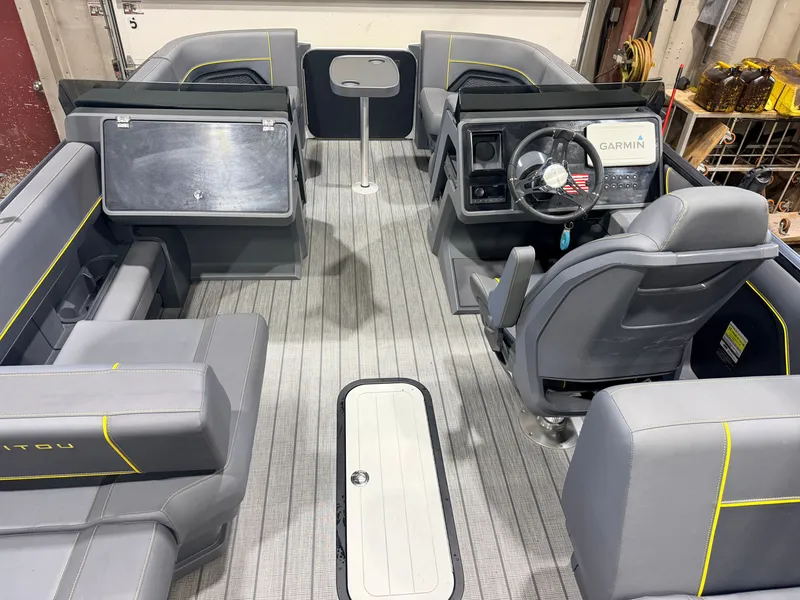 Slide: The Image of The image shows the interior of a 2023 Manitou 22 Explore Tritoon with gray seating and a helm. - 5