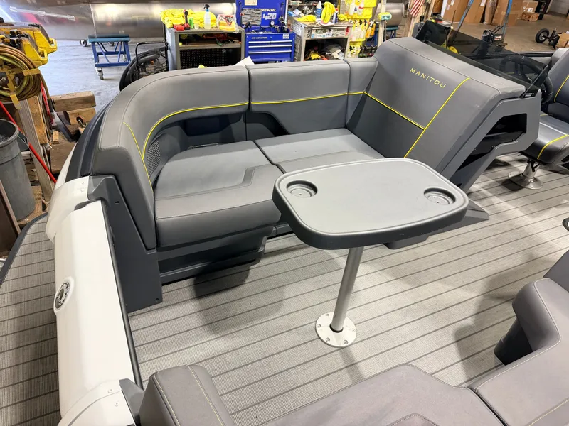 Slide: The Image of Interior of a 2023 Manitou 22 Explore Tritoon with gray seating and a table. - 13