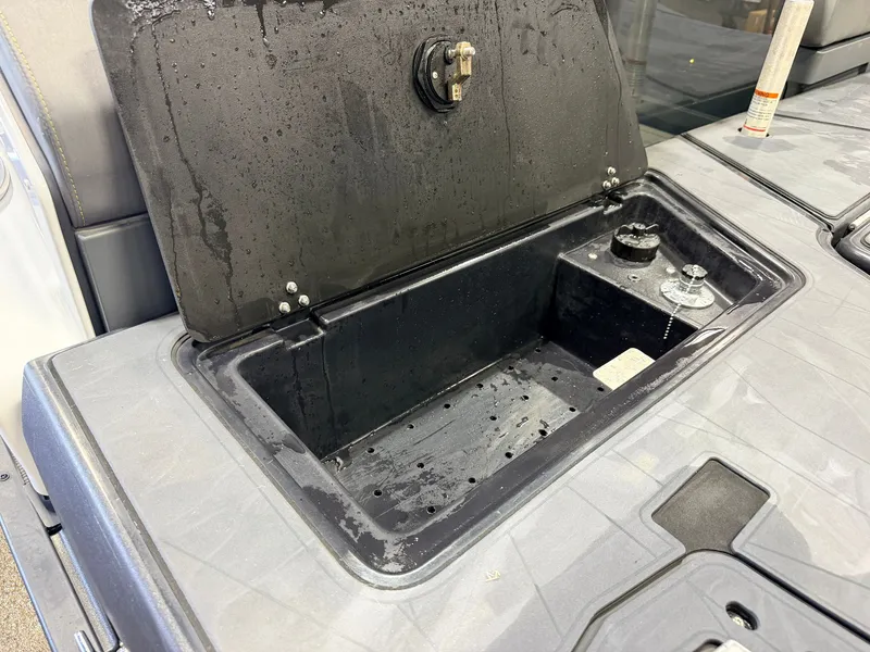Slide: The Image of An open storage compartment on a boat with a wet surface and a fuel cap. - 48