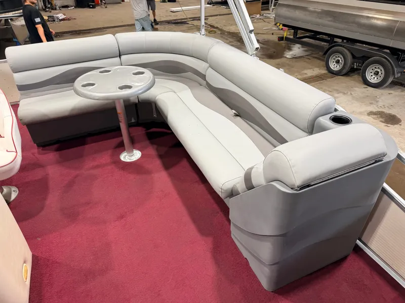 Slide: The Image of A gray, curved seating sofa with a round table on red carpet flooring. - 28