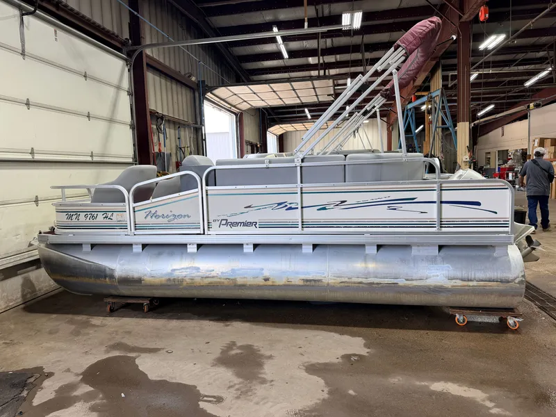 Slide: The Image of A 1998 Premier 180 Horizon pontoon boat with a 40HP Honda 4-stroke engine in a workshop. - 40