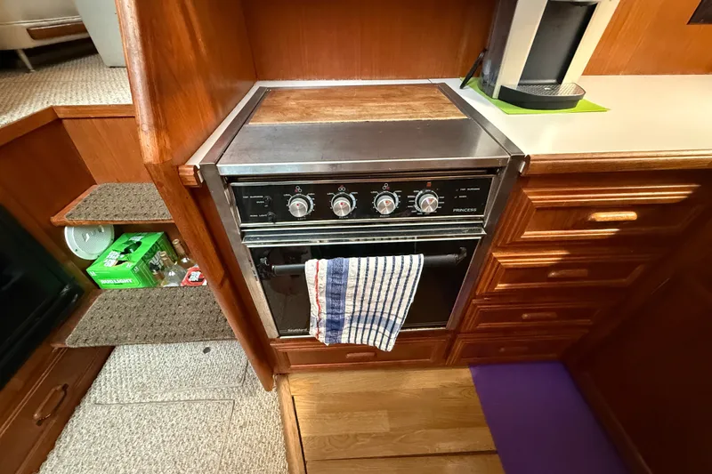 Slide: The Image of 1989 Carver 3807 Aft Cabin Motor Yacht kitchen with stove, wooden cabinets, and striped towel. - 45