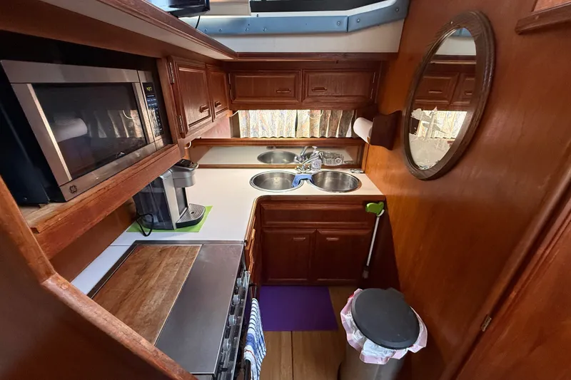 Slide: The Image of 1989 Carver 3807 Aft Cabin Motor Yacht kitchen with microwave, sink, and wooden cabinetry. - 43