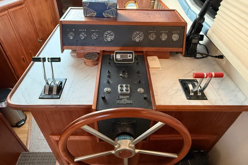 Slide: The Image of 1989 Carver 3807 Aft Cabin Motor Yacht helm with wooden wheel and control panel. - 38