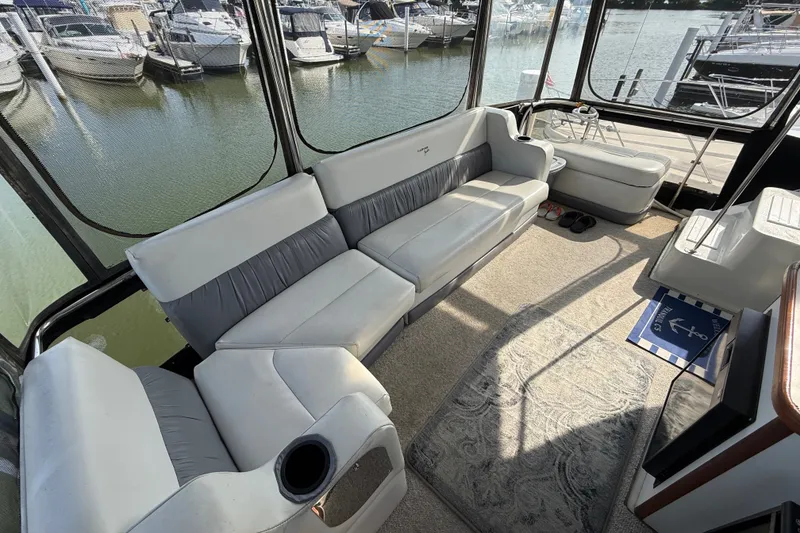 Slide: The Image of 1989 Carver 3807 Aft Cabin Motor Yacht interior with plush seating and marina view. - 8