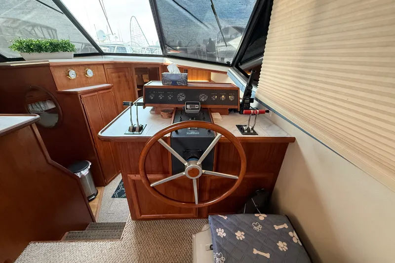 Slide: The Image of 1989 Carver 3807 Aft Cabin Motor Yacht helm with wooden steering wheel and control panel. - 32